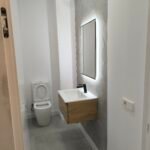 Baño reformado con mueble de lavabo de madera y espejo iluminado en Palma