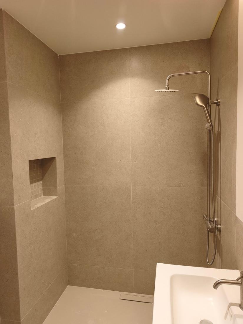 Ducha de obra terminada con nicho integrado, sumidero lineal y columna termostática en una reforma de baño en Palma